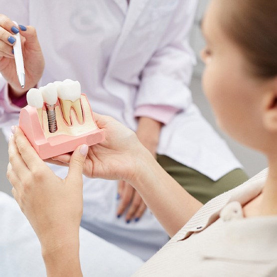 A dentist showing a dental implant model to a patient