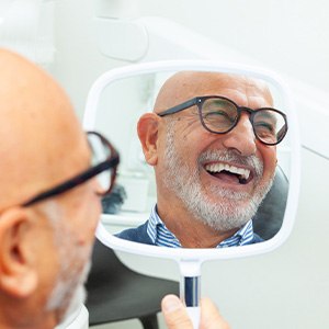 Man with black glasses smiling in reflection in mirror