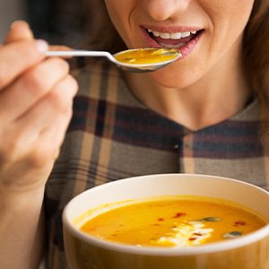 A closeup of a woman eating soup