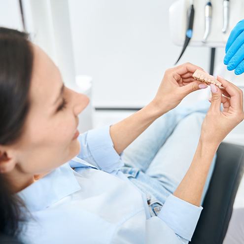 A woman looking at a dental bridge