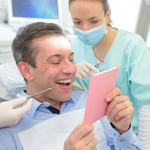 A man admiring his dental bridge in the mirror