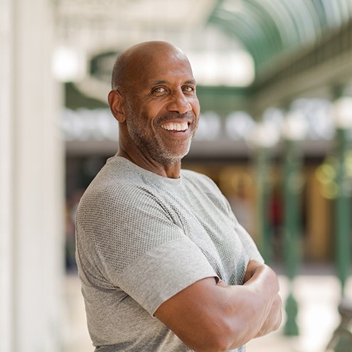 Man in gray shirt smiling outside